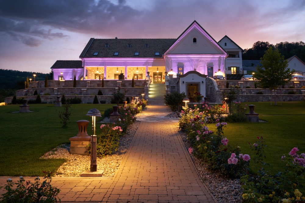 white house with lighting and lit garden with pink flowers