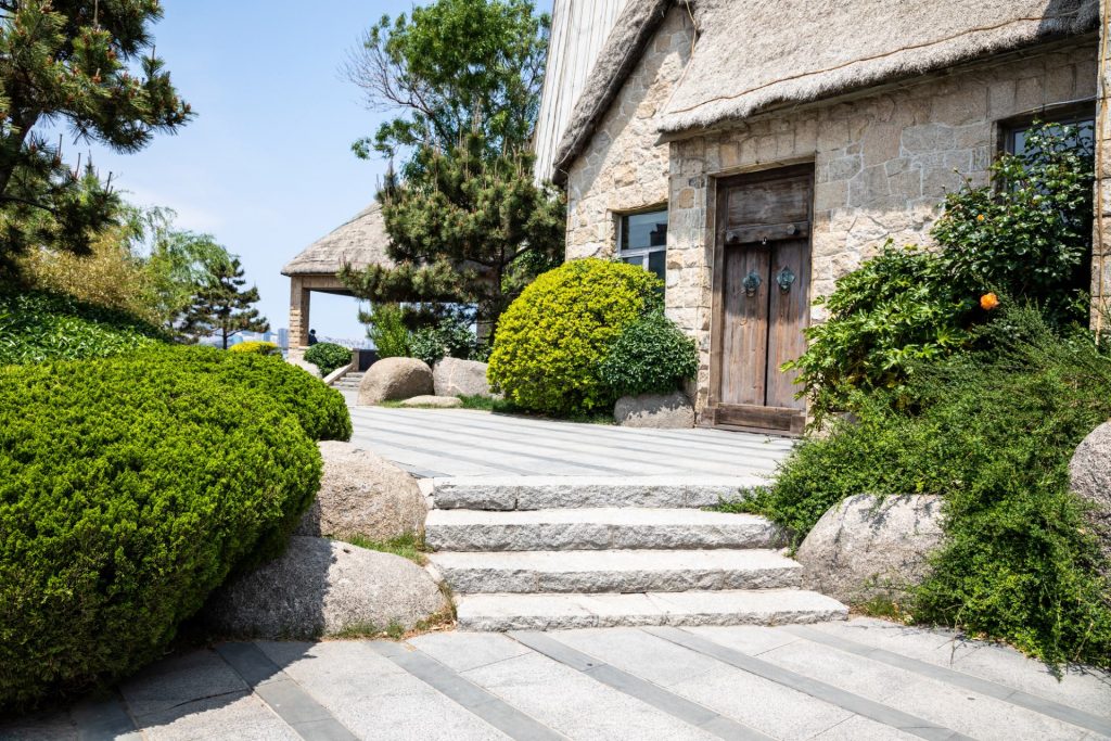 gray paved area with stone house and brown wooden doors