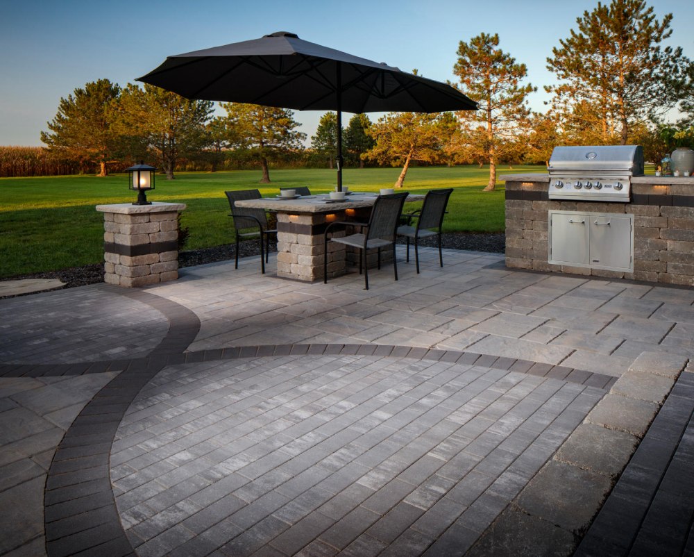 paved patio with table and chairs with black umbrella