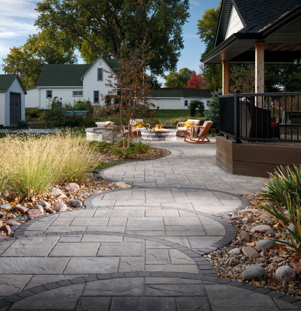 gray paved walkway with brown rocking chair and firepit