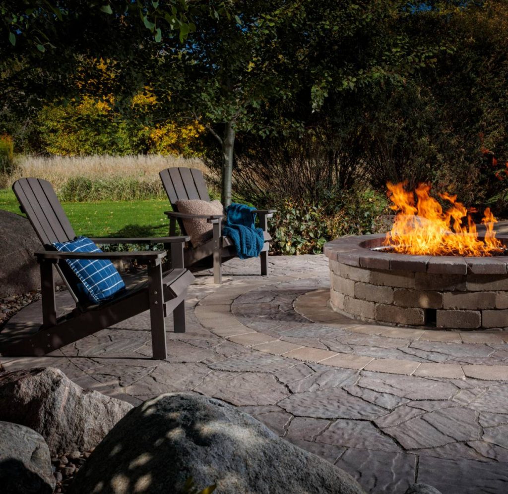 burning firepit with brown chairs and blue cover and pillow