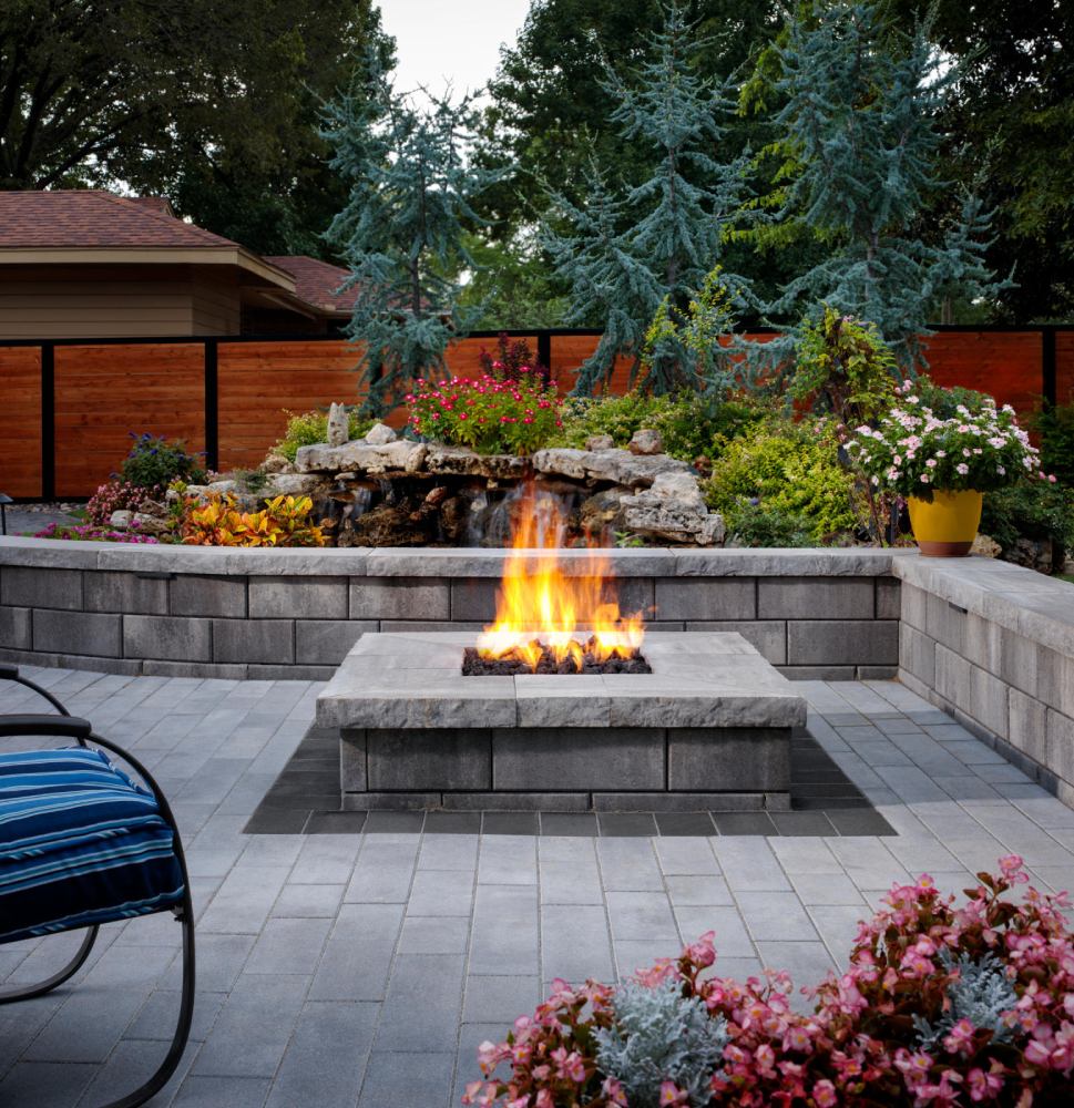 gray paved area with gray firepit and striped cushioned chair