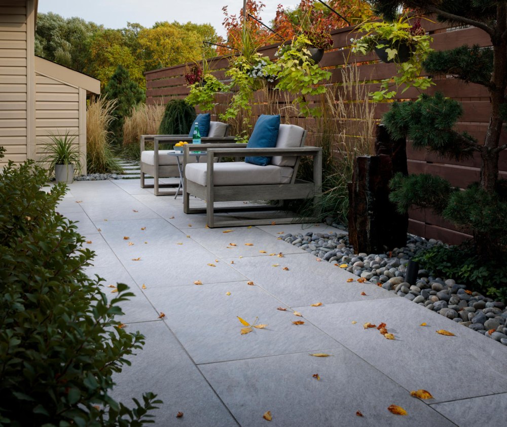 paved walkway with wooden cushioned chairs and blue pillows