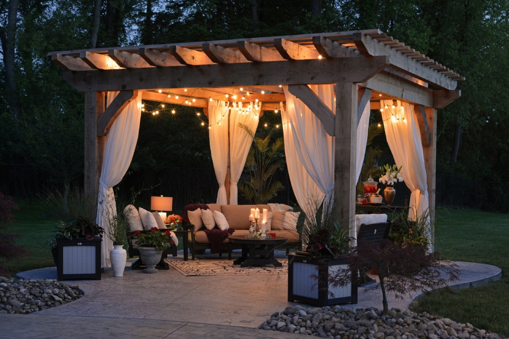 wooden pergola with lighting and cushioned couch and chairs